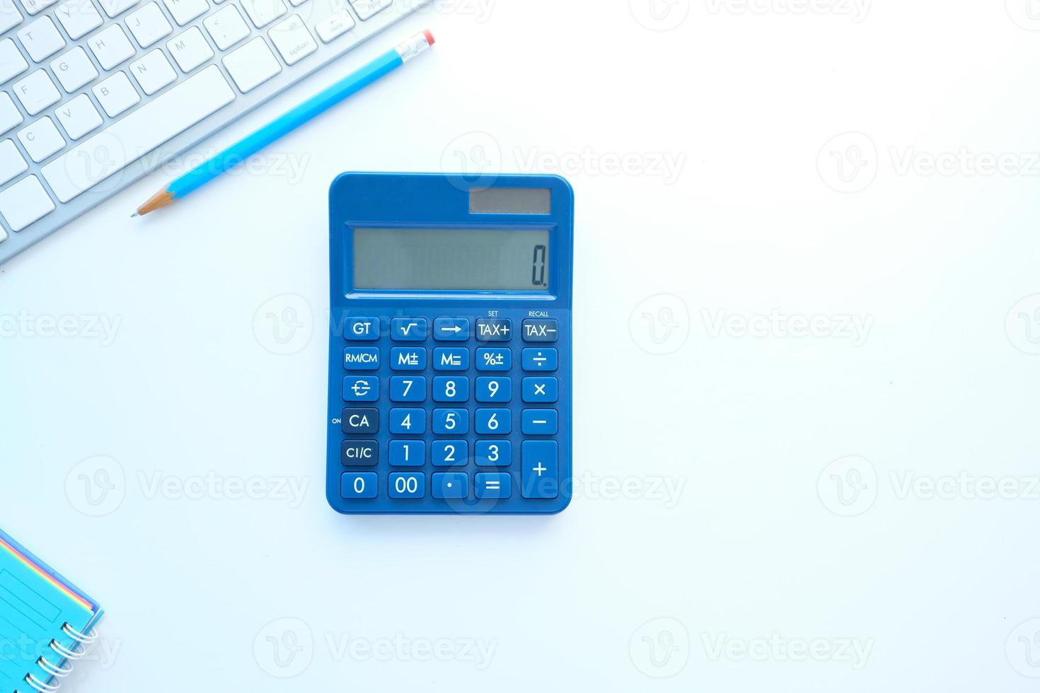 close up de calculadora azul e teclado em fundo branco foto