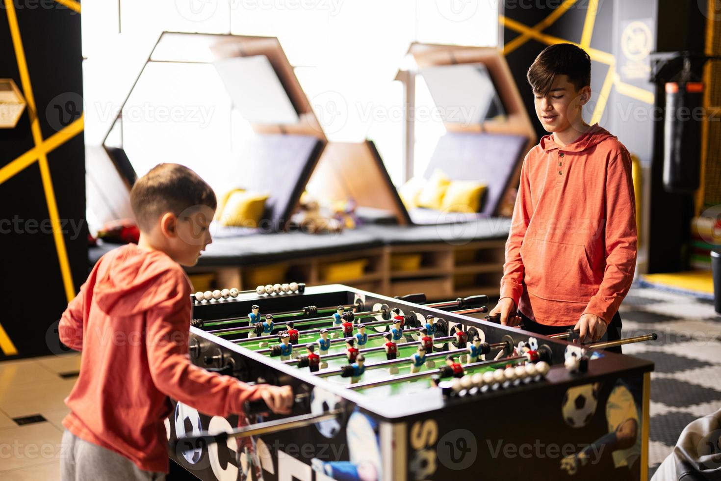 irmãos jogando mesa futebol dentro crianças jogar Centro. foto