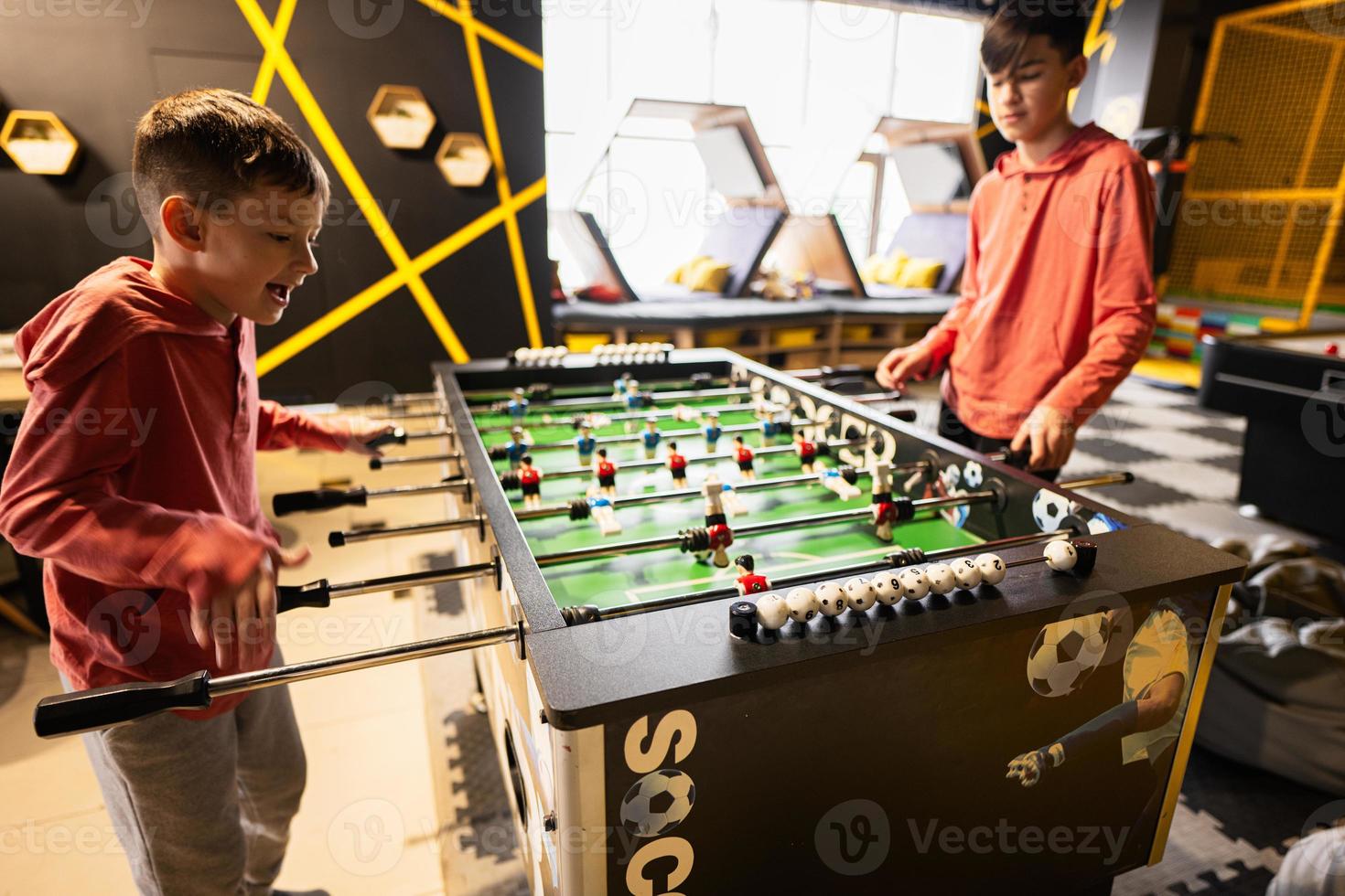 irmãos jogando mesa futebol dentro crianças jogar Centro. foto