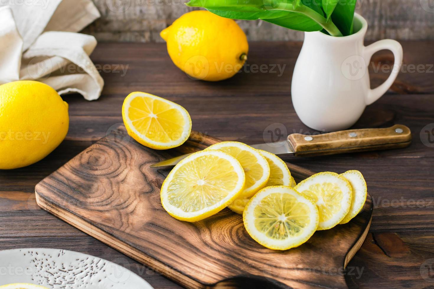 corte maduro limões com uma faca em uma de madeira corte borda em a mesa. orgânico nutrição, fonte do vitaminas. foto