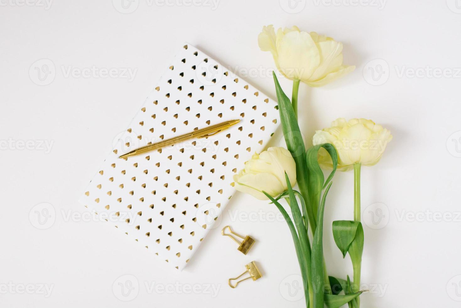 plano deitar Primavera flores amarelo tulipas, copo do café branco em branco álbum caderno escrevendo caneta em branco fundo. adorável cumprimento cartão para marcha 8 mães dia feriado aniversário. mulher trabalhando escrivaninha foto