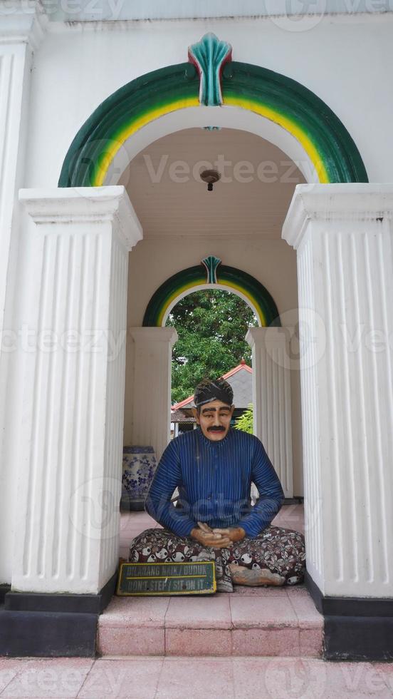 uma estátua do uma real guarda sentado de pernas cruzadas dentro frente do a real porta foto