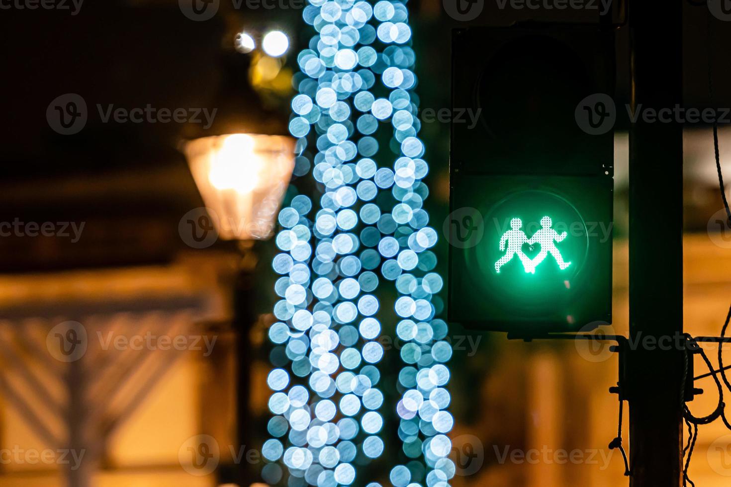 semáforo para pedestres com luz verde e luzes desfocadas da árvore de natal foto