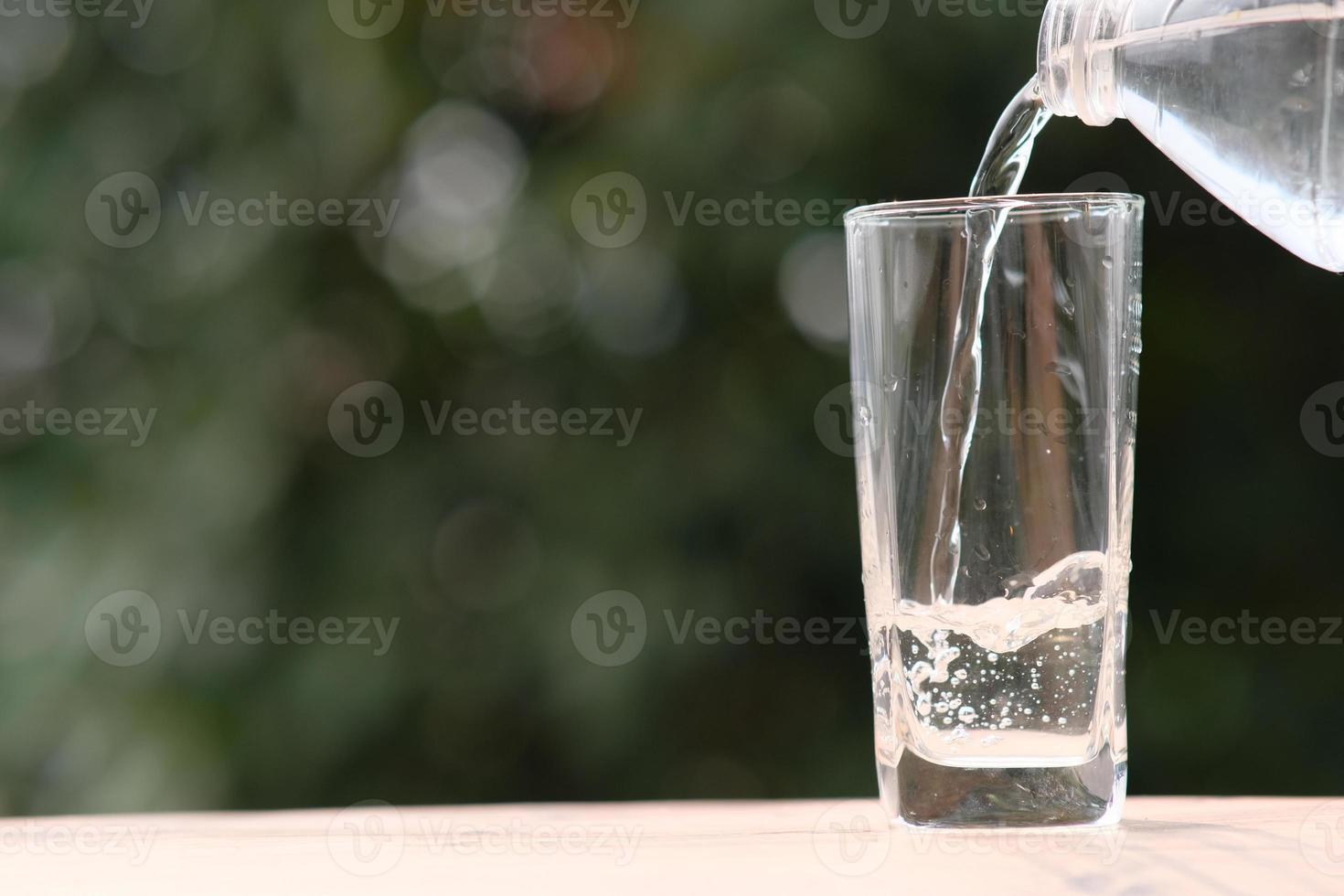 água mineral potável na mesa de madeira e água no vidro foto