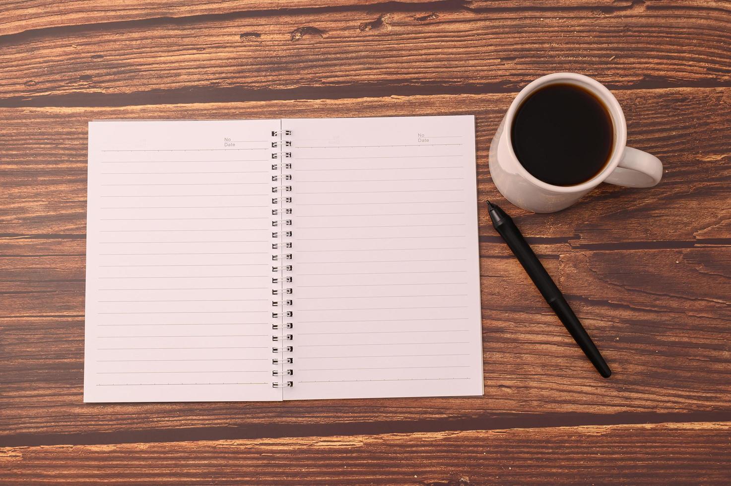café e um caderno com uma caneta sobre uma mesa de madeira foto