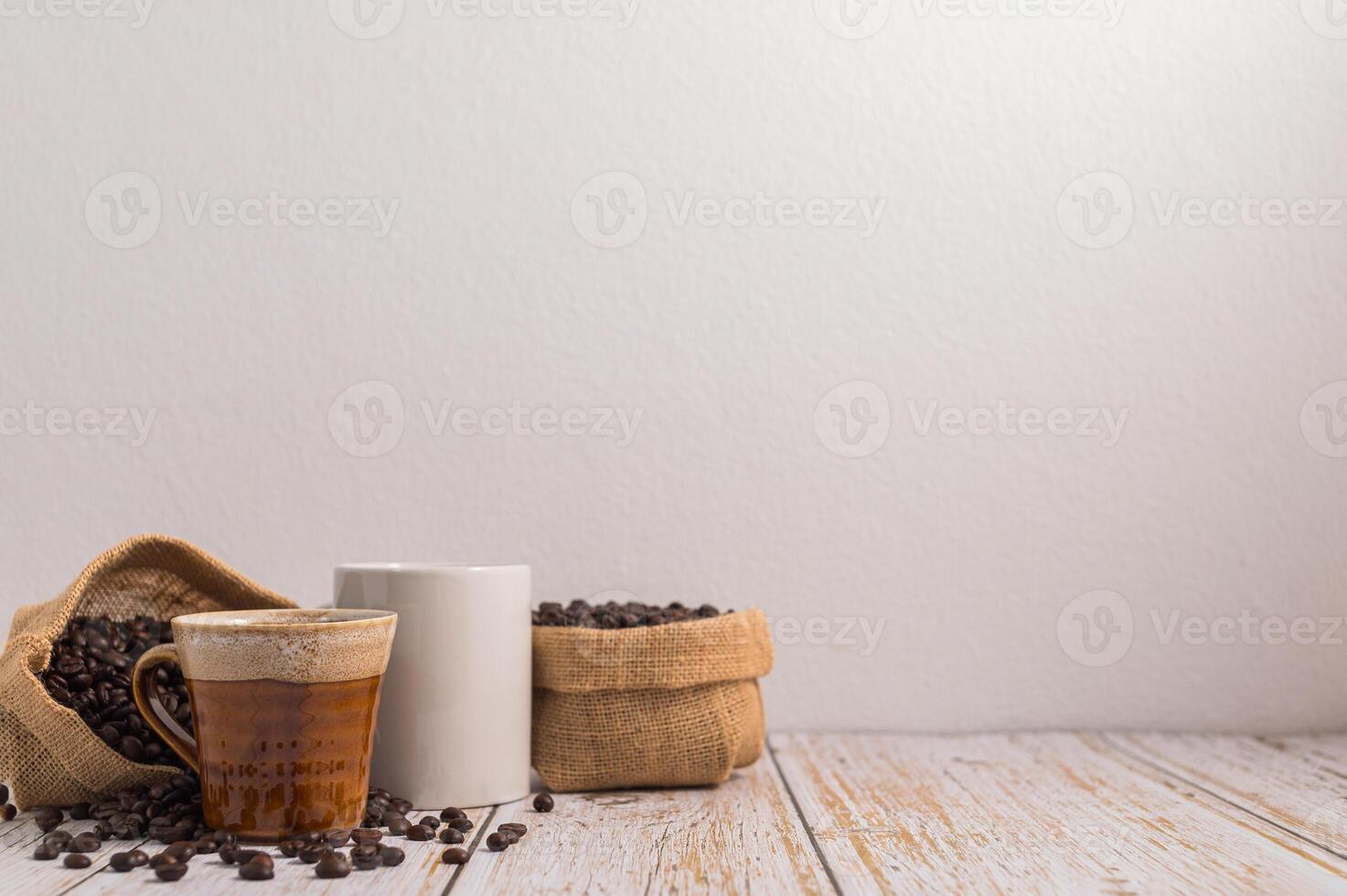 canecas de café e sacos de grãos de café em uma mesa de madeira foto