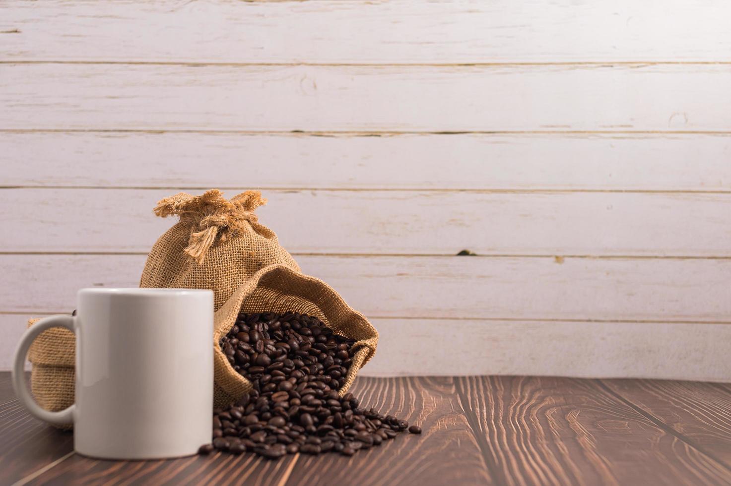 uma caneca de café e sacos de grãos de café em uma mesa de madeira foto