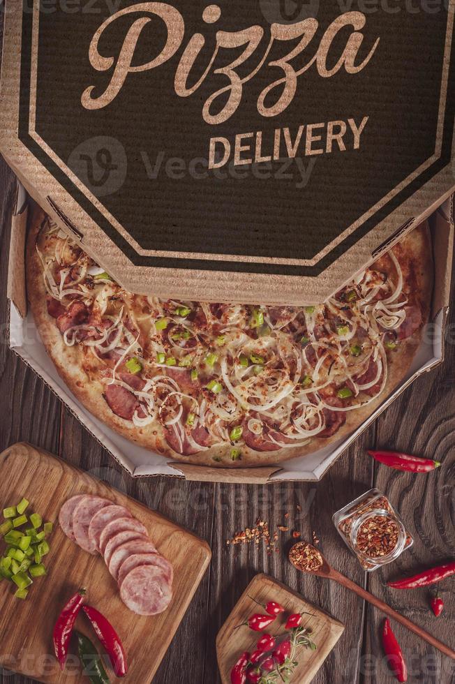 pizza com mussarela, linguiça calabresa, pimenta verde, cebola e pimenta calabresa em uma caixa de entrega foto