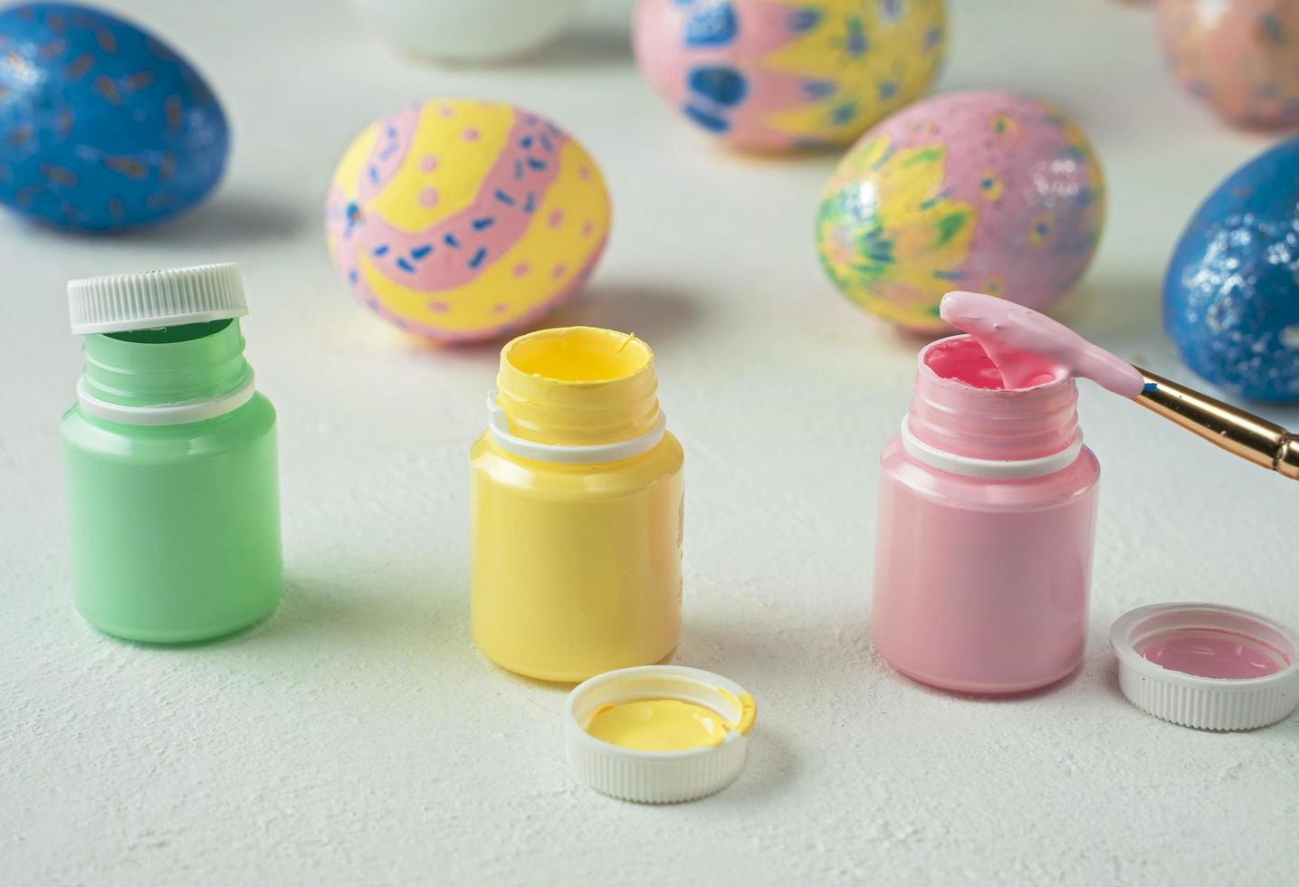 abra latas de tinta para pintar ovos de páscoa em um fundo branco foto