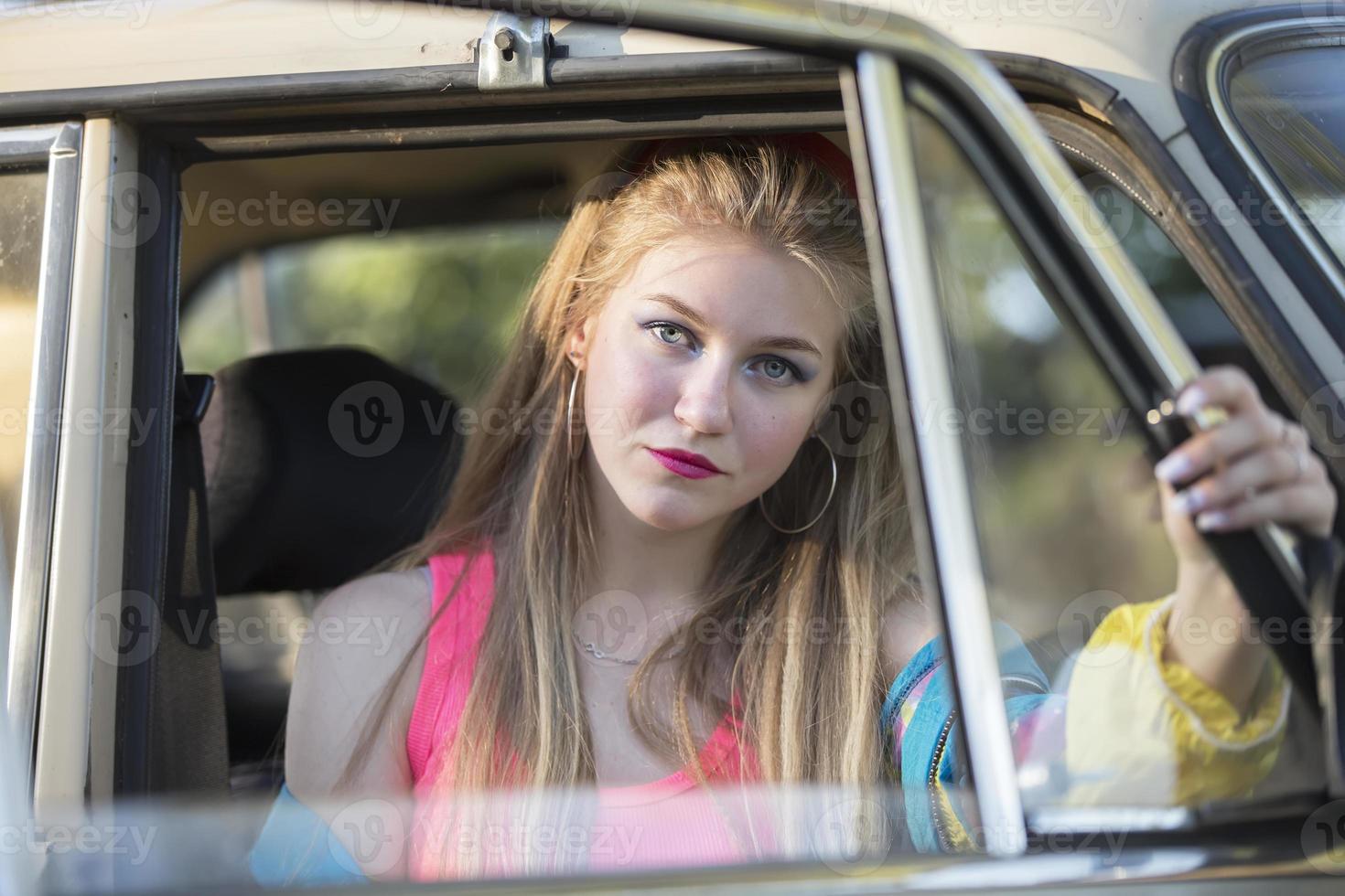 uma lindo Loiras menina com grandes cabelo parece Fora do a carro janela. foto