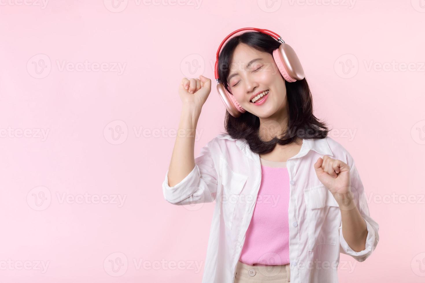 sorrir bonita ásia modelo pessoa ouço música música e apreciar dança com sem fio fone de ouvido conectados audio rádio som. positivo Diversão saiu alegre juventude fêmea mulher em Rosa isolado fundo estúdio foto