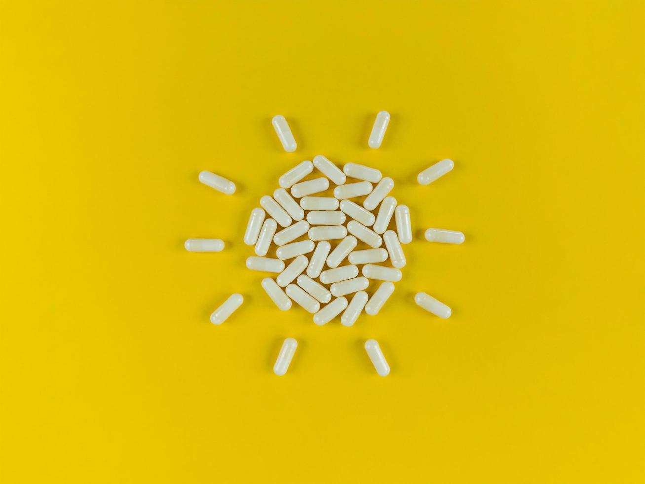 formato de sol feito com cápsulas de comprimidos brancos em um fundo amarelo foto