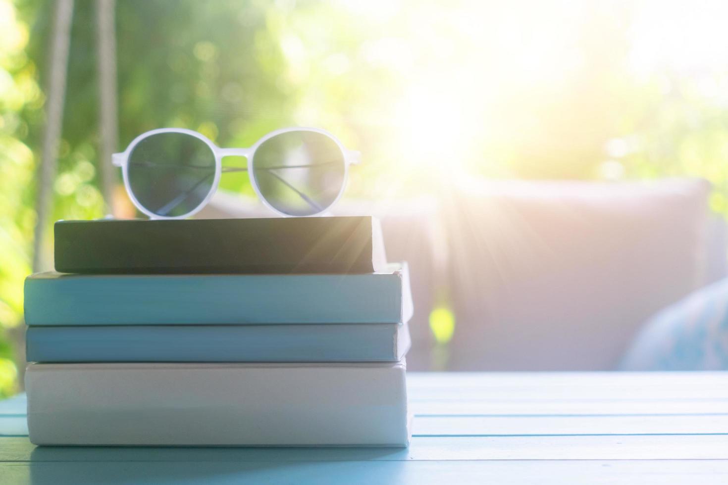 livros sobre uma mesa com óculos de sol no topo em um quarto de resort de férias, leitura e conceito de educação de terapia relaxante foto