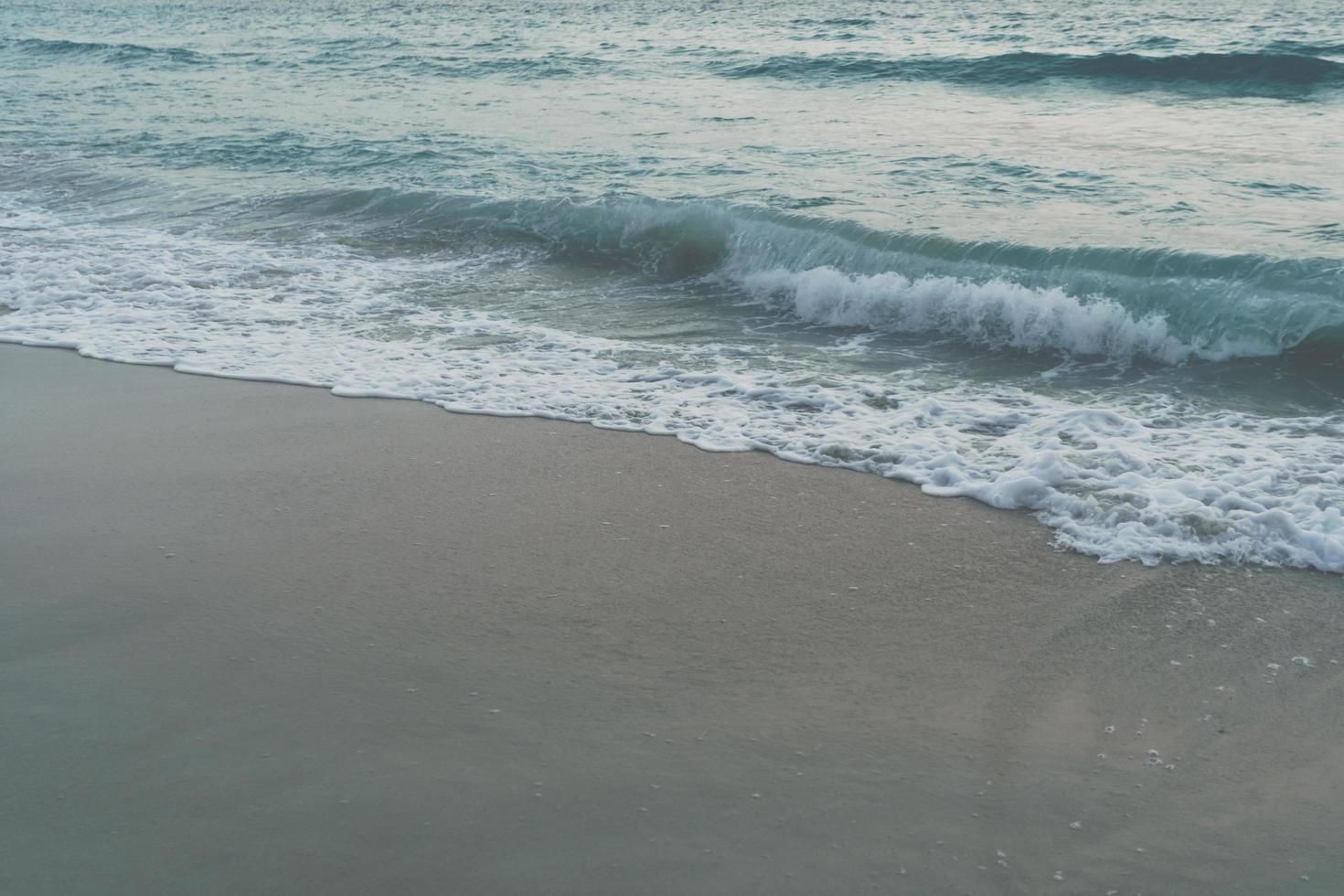 tom vintage desbotado das ondas do mar na praia durante o verão foto