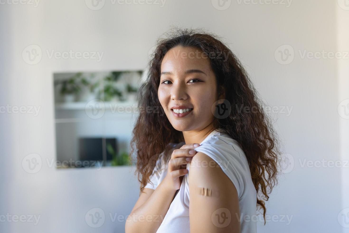 mulher apontando às dela braço com uma curativo depois de recebendo a covid-19 vacina. ásia mulher mostrando dela ombro depois de obtendo coronavírus vacina foto