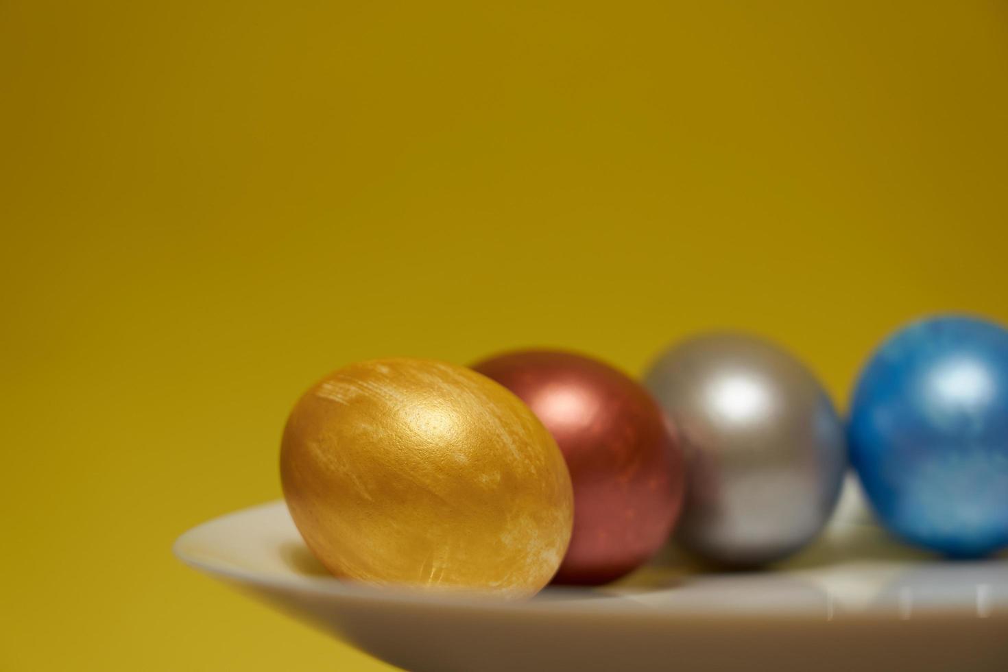 ovos pintados em um prato branco com um fundo amarelo para a Páscoa foto