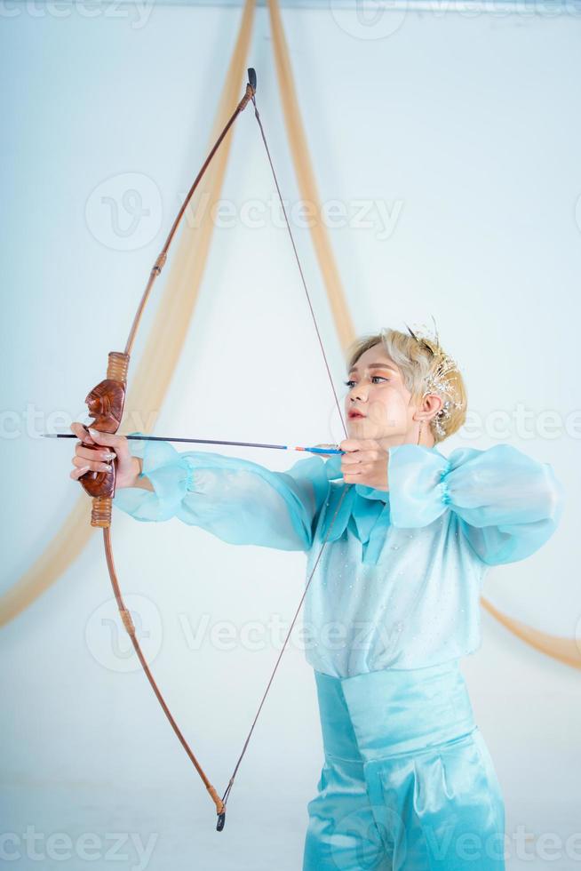 a ásia mulher com Loiras cabelo segurando a seta enquanto vestindo uma azul vestir foto