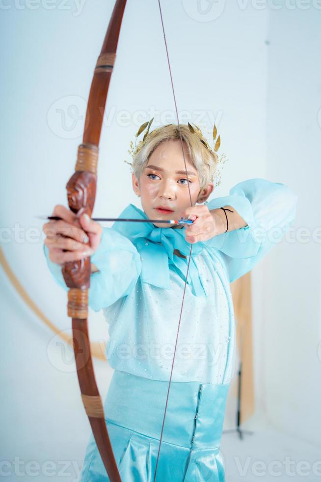 uma Princesa dentro uma azul vestir puxar uma arco com dela mão foto