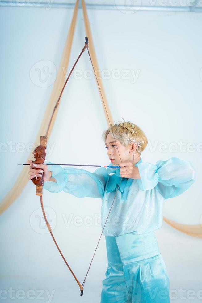 a ásia mulher com Loiras cabelo segurando a seta enquanto vestindo uma azul vestir foto