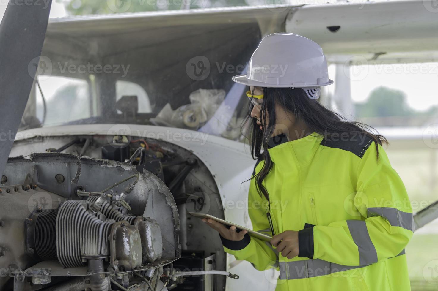 técnico consertando o motor do avião, engenharia aeroespacial feminina verificando motores de aeronaves, manutenção mecânica asiática inspeciona motor de avião foto