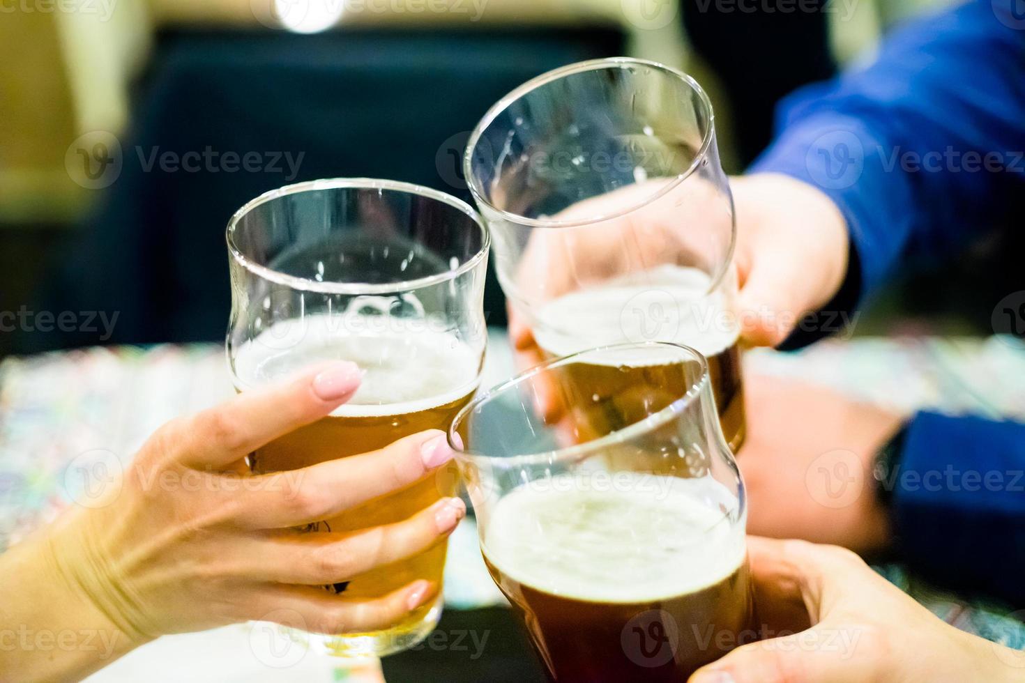 três pessoas tilintando copos de cerveja foto