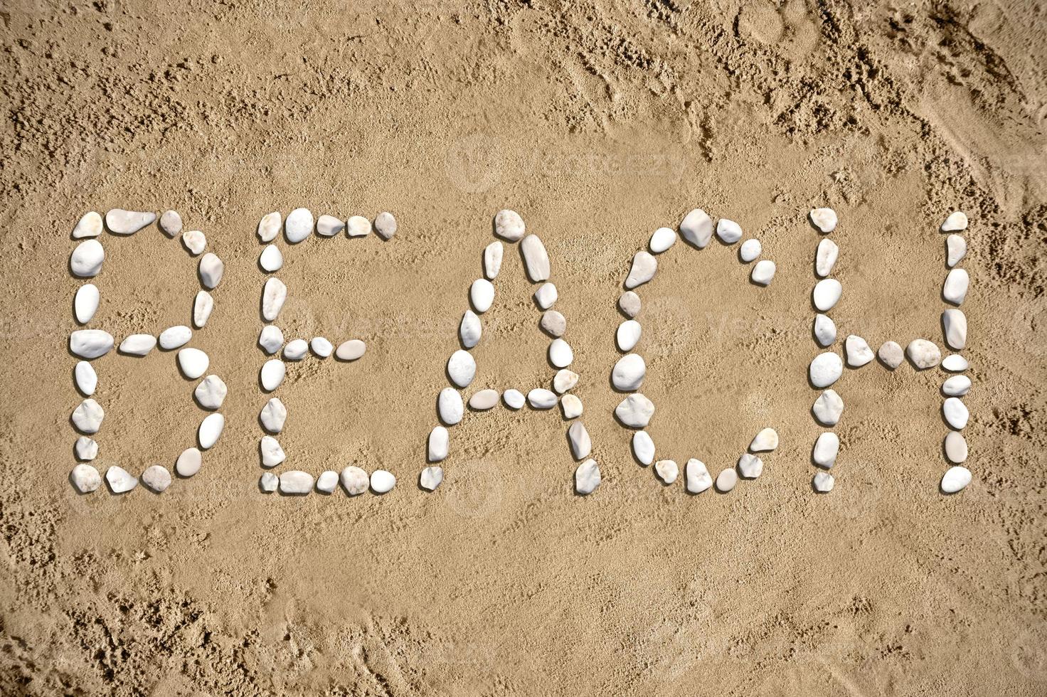 de praia - palavra fez com pedras em areia foto