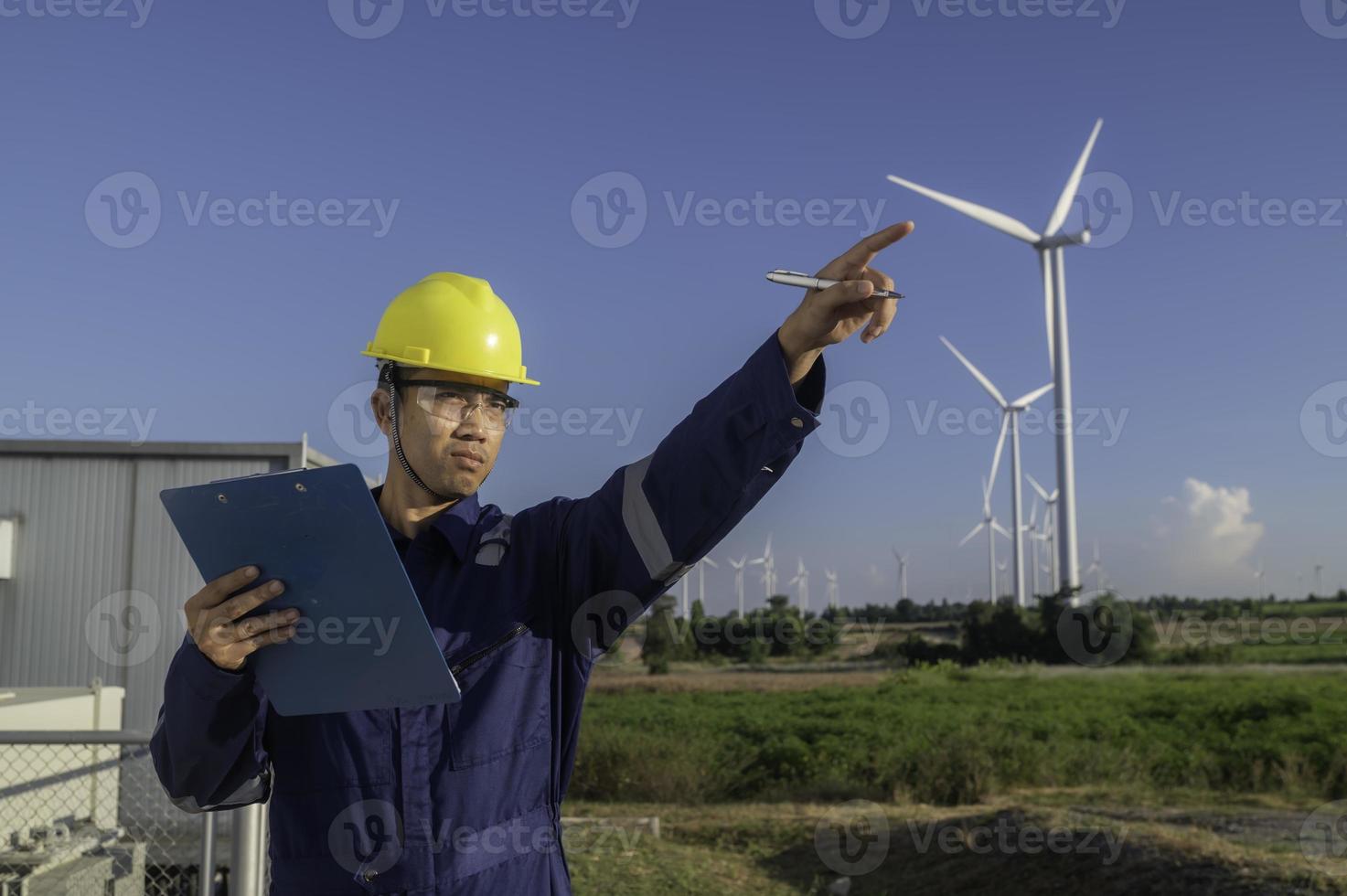 engenheiros de homem asiático trabalhando e segurando o relatório na estação de gerador de energia de turbina eólica na montanha, tailândia, homem técnico no local de trabalho foto