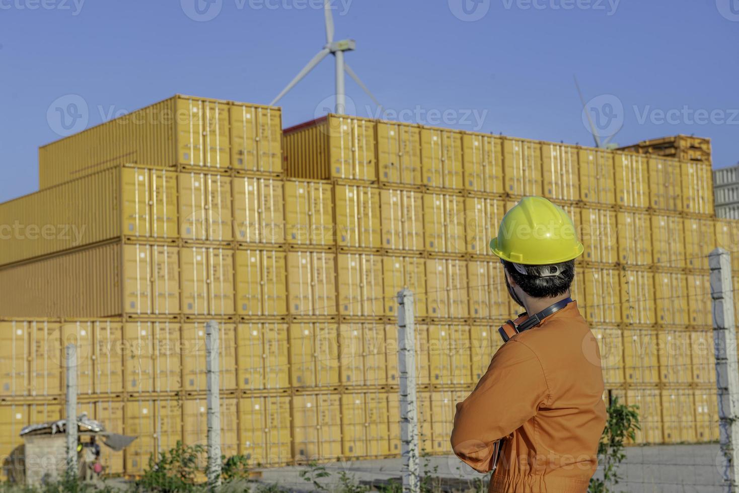 engenheiro trabalhando no local para manter o contêiner, capataz usando capacete de pé no pátio de contêineres e verificando a integridade do contêiner foto