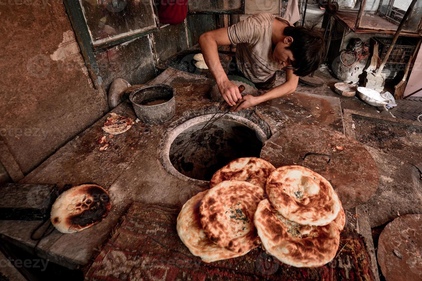 a velho fornecedor vendendo cozido naan em a velho rua do kashgar foto