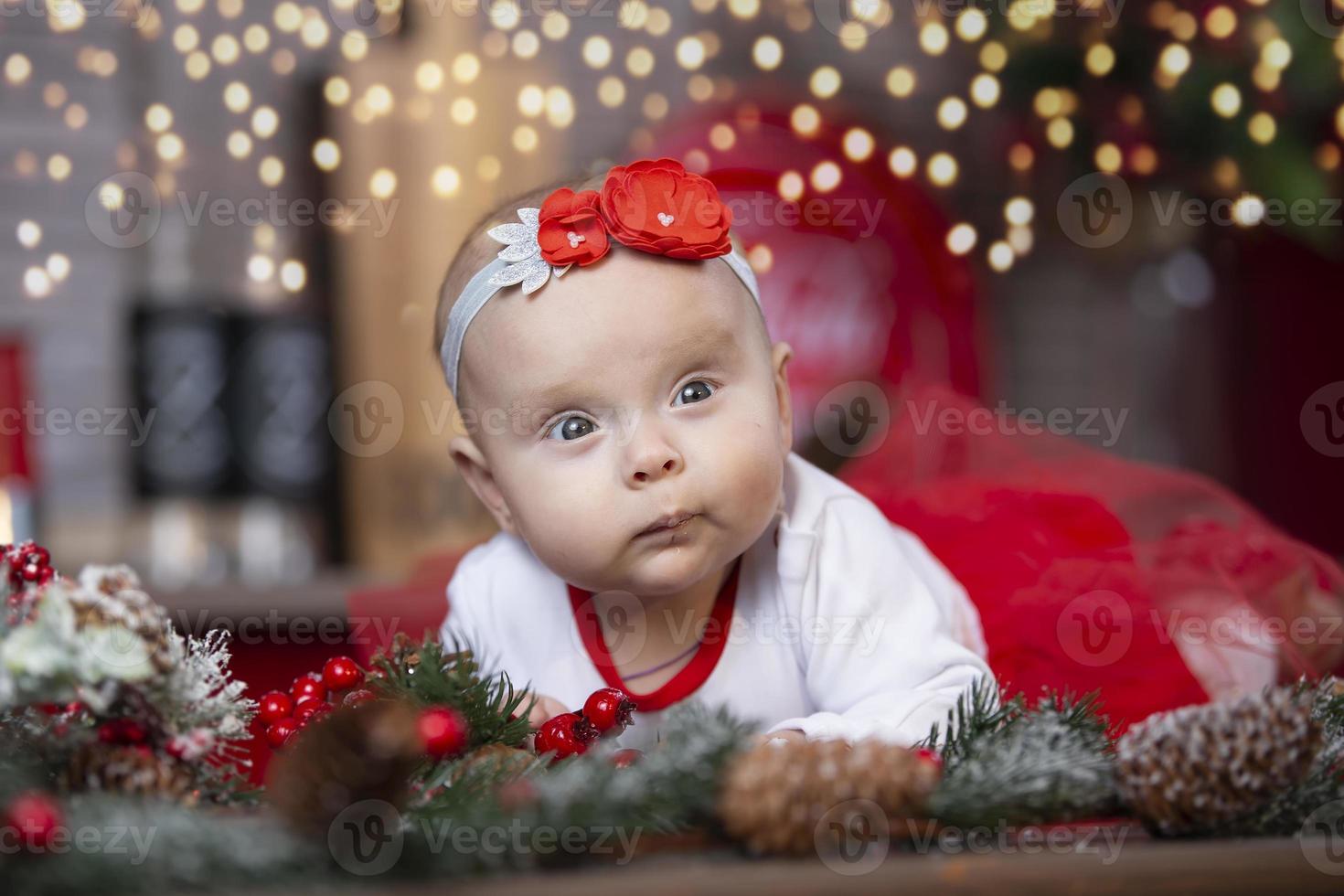 pequeno bebê às Natal. criança de três meses menina contra a fundo do a Natal árvore decoração. foto