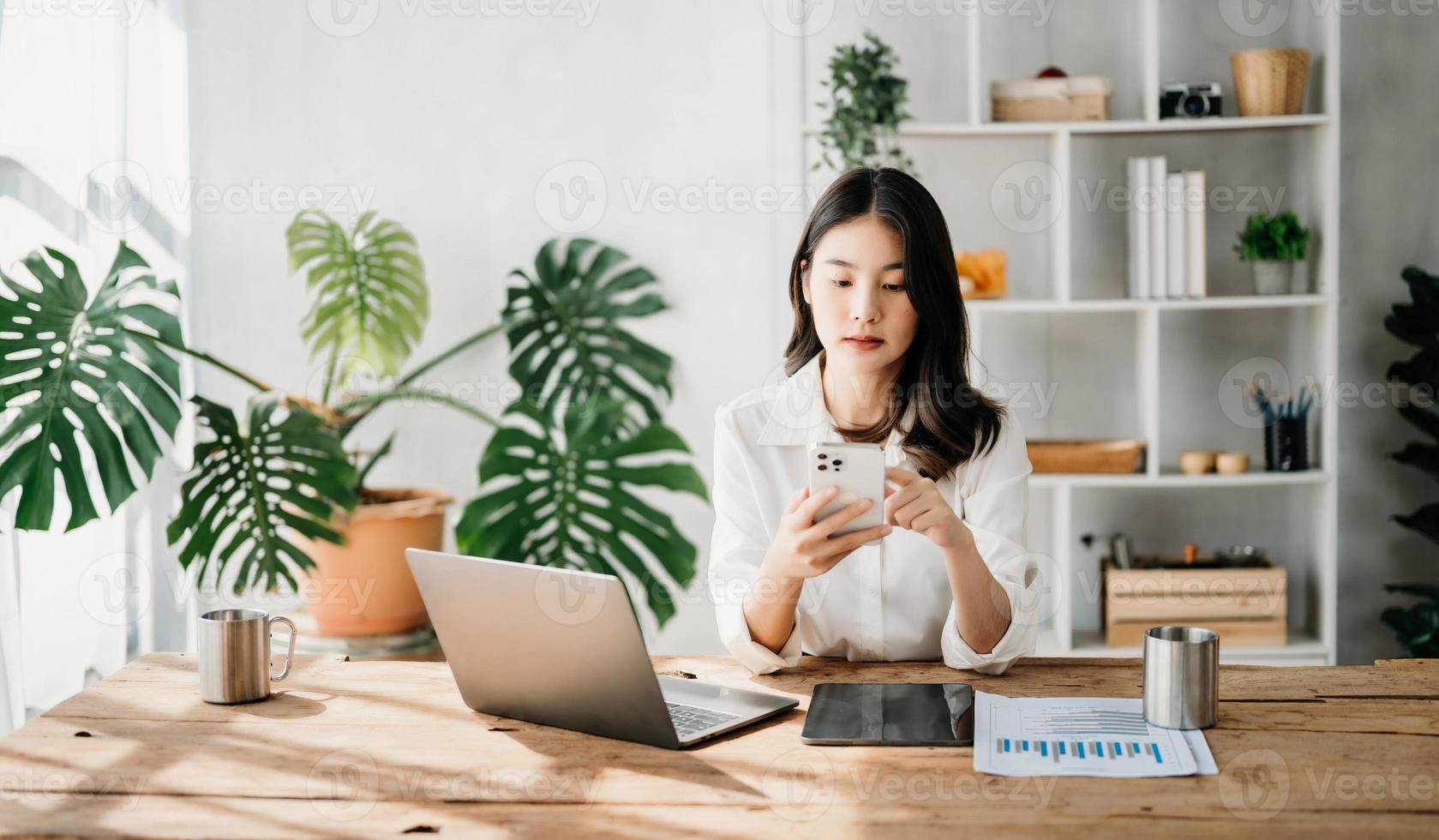 trabalhando mulher conceito uma fêmea Gerente atendendo vídeo conferência e segurando tábua, smatrphone e copo do café dentro casa escritório foto