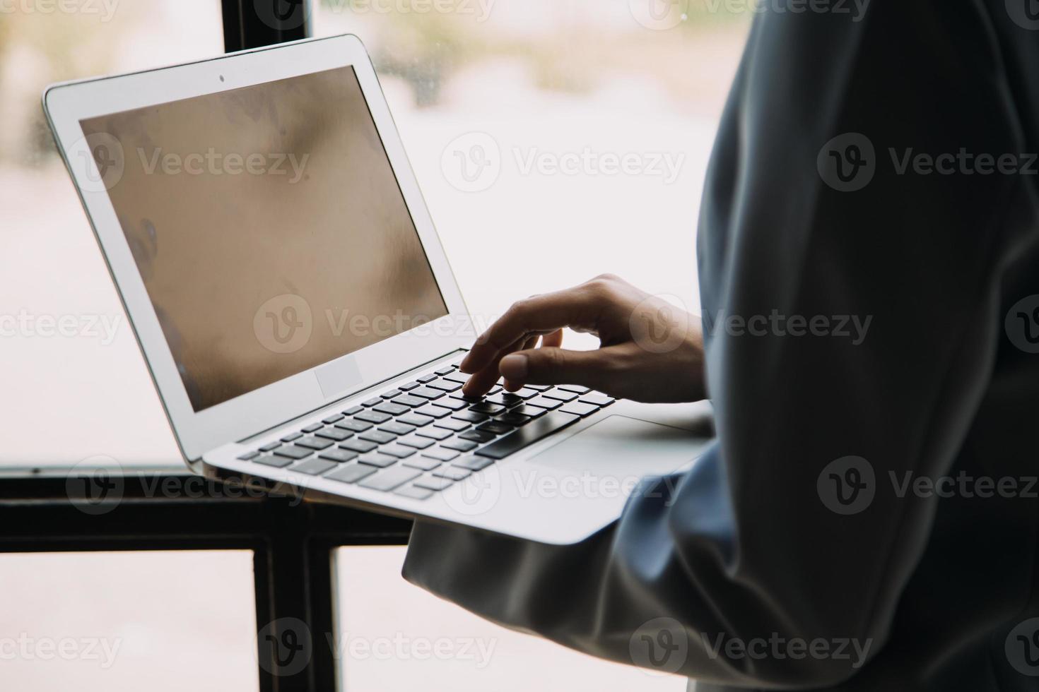 atraente sorridente jovem ásia o negócio mulher trabalhos às casa escritório, ásia mulher trabalhando em computador portátil computador segurando tábua. foto