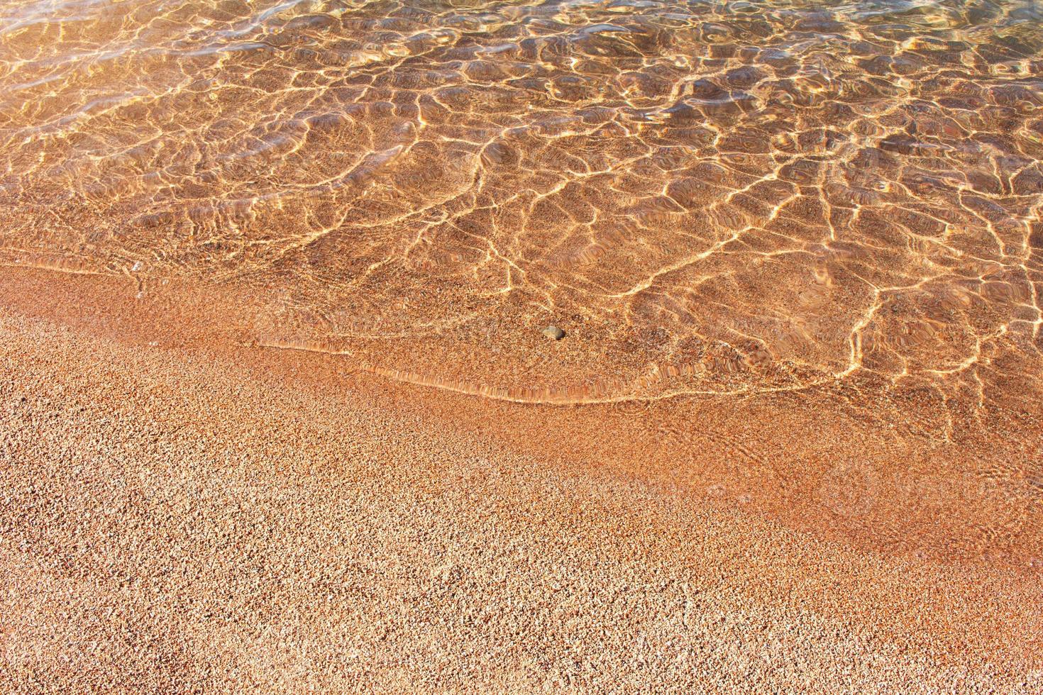 arenoso de praia com seixo e mar com ondulações e onda fundo. ensolarado dia. viagem, verão dentro quente países. cópia de espaço foto