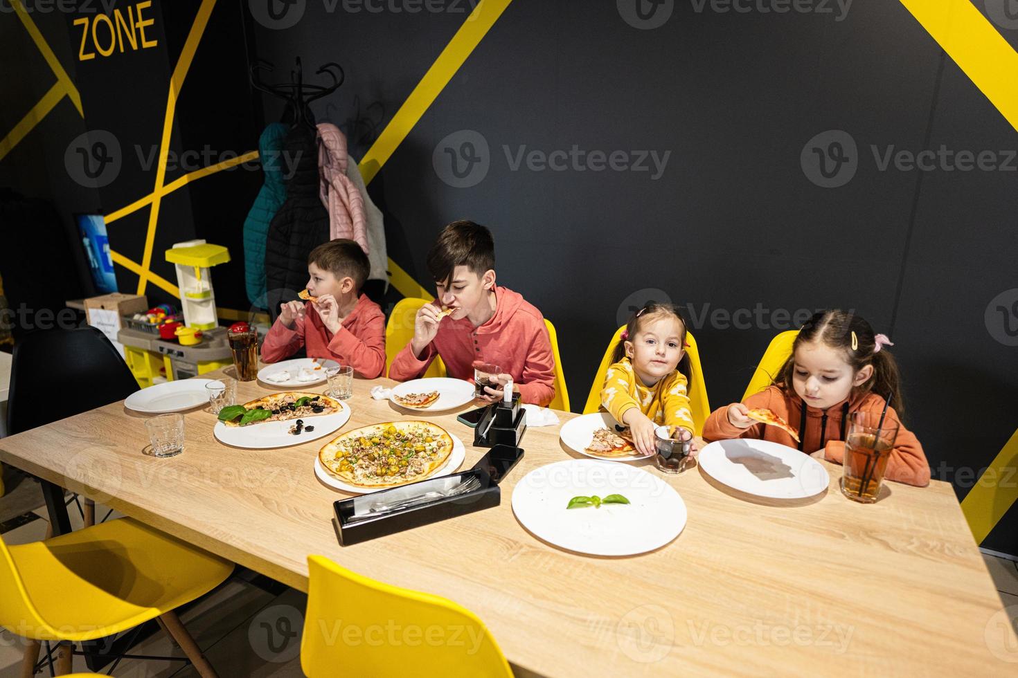 quatro crianças comendo italiano pizza dentro pizzaria. crianças comer às cafeteria. foto