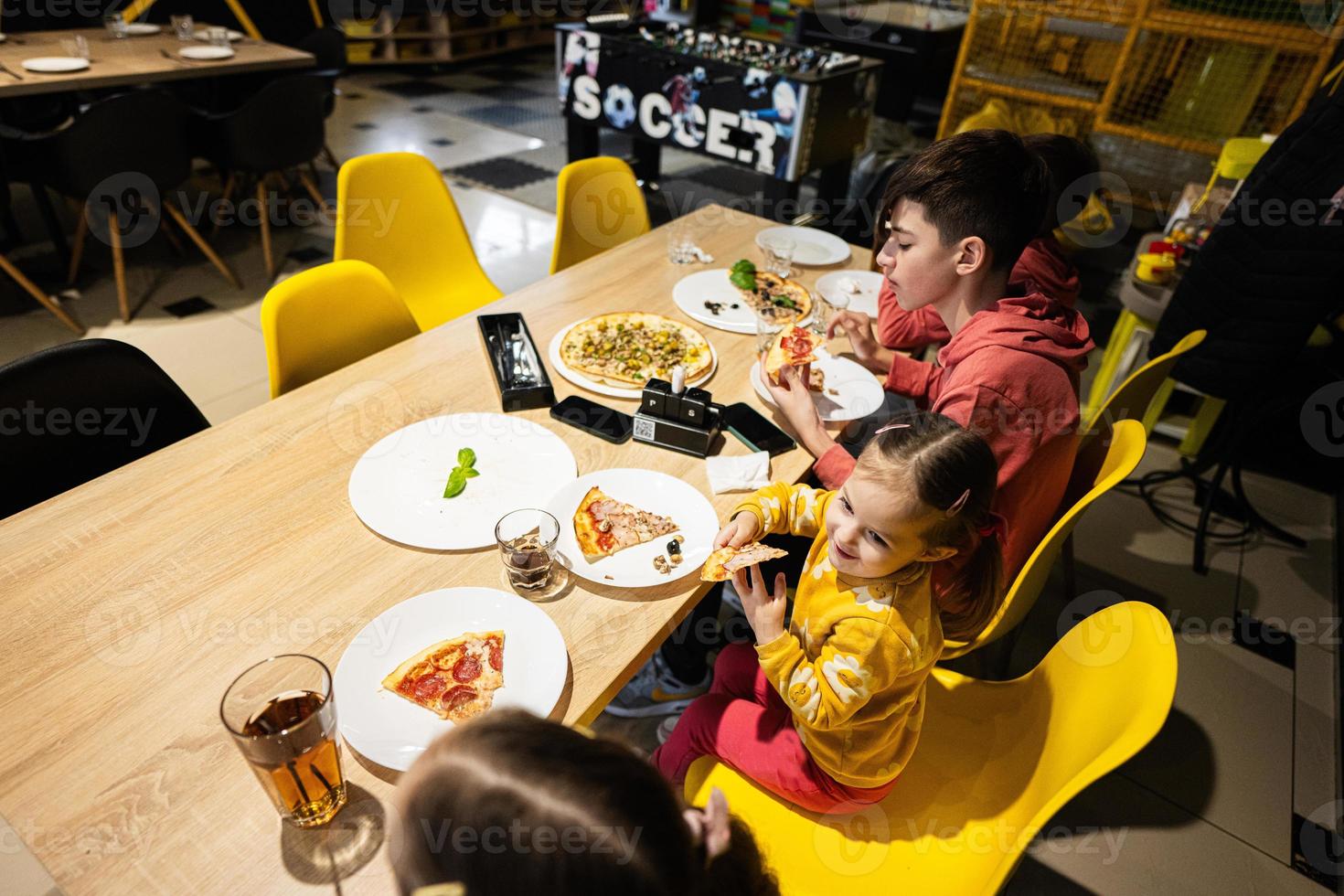 quatro crianças comendo italiano pizza dentro pizzaria. crianças comer às cafeteria. foto