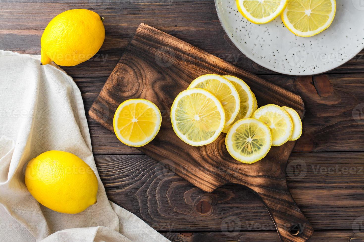 fatiado volta peças do limão em uma corte borda e todo limões em uma de madeira mesa. orgânico nutrição, fonte do vitaminas. topo Visão foto