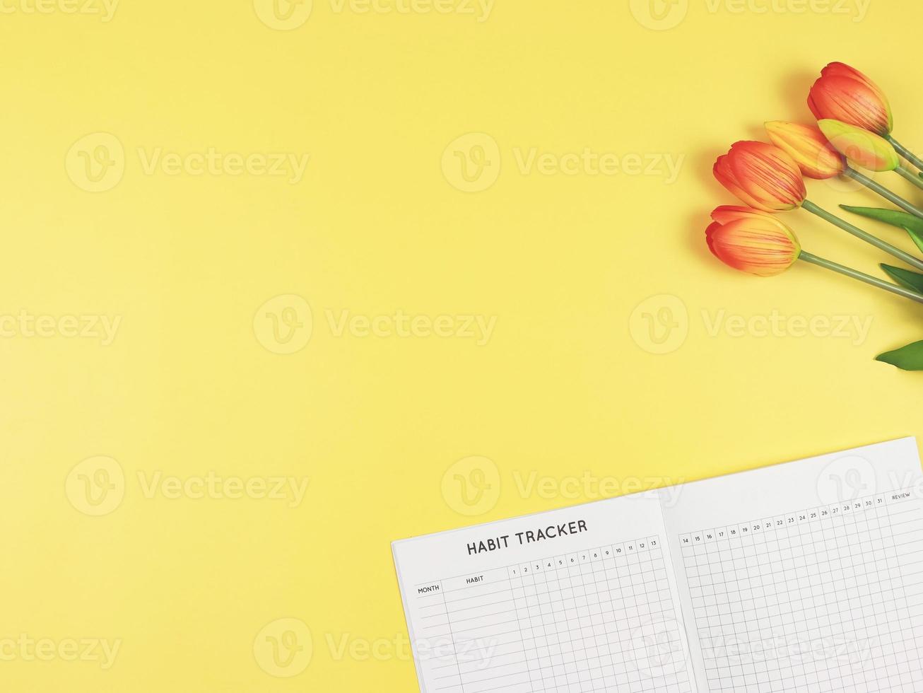 plano disposição do hábito rastreador livro, e tulipas em amarelo fundo. foto