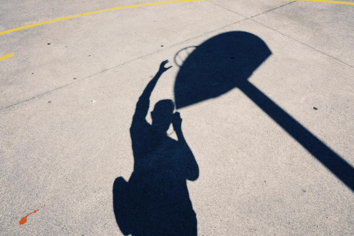 sombra do homem no chão jogando basquete foto
