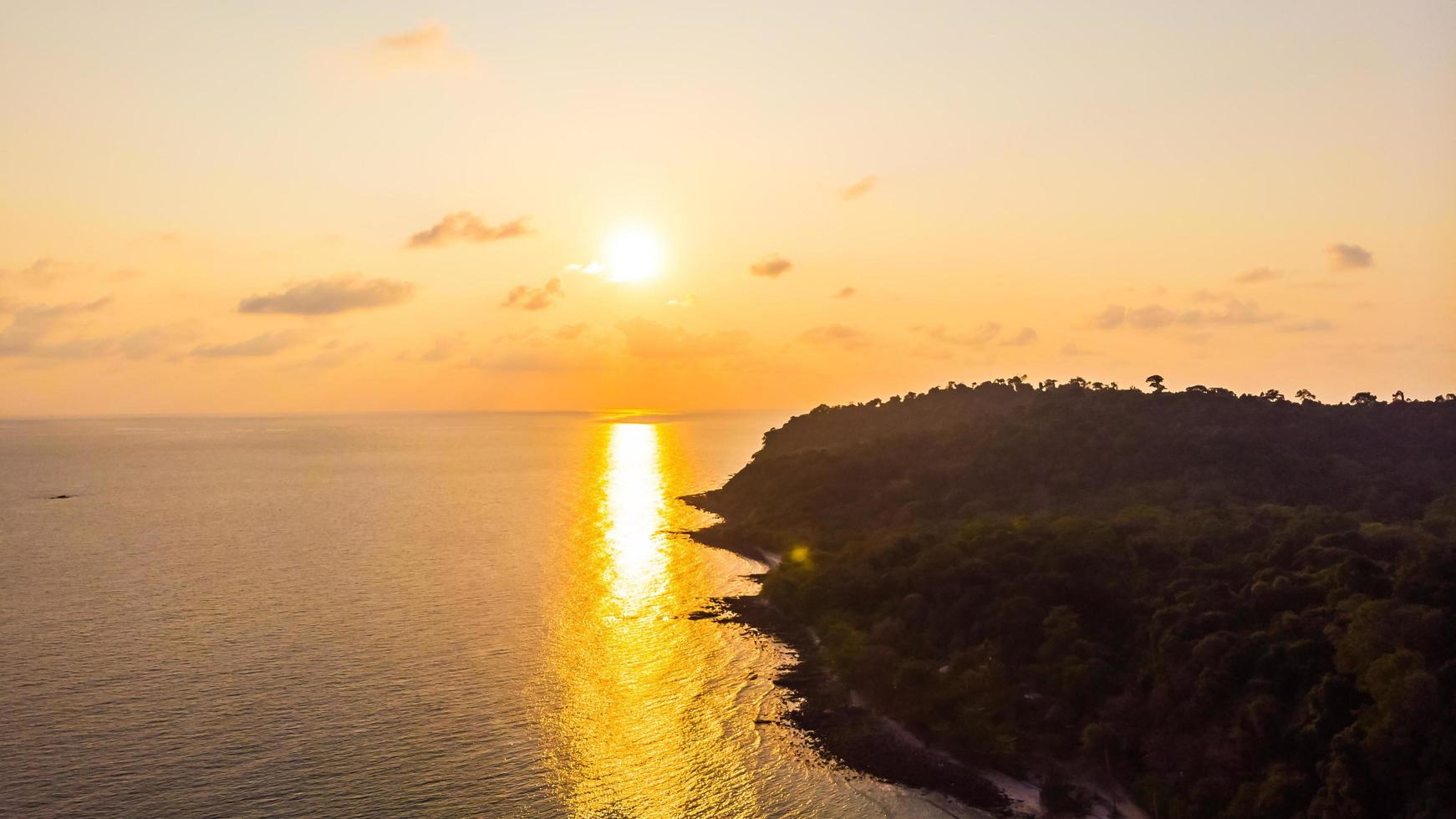 vista aérea da bela praia e do mar com coqueiro ao pôr do sol foto