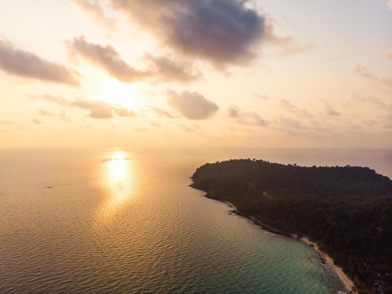 vista aérea da bela praia e do mar com coqueiro ao pôr do sol foto