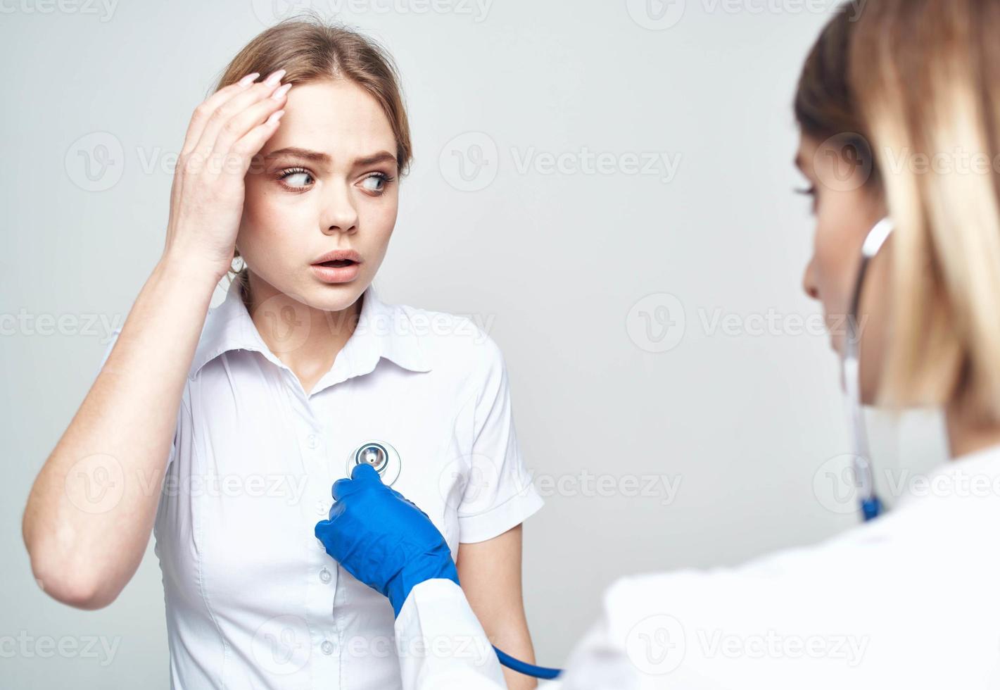 mulher paciente reclama do dor de cabeça para médico com estetoscópio foto