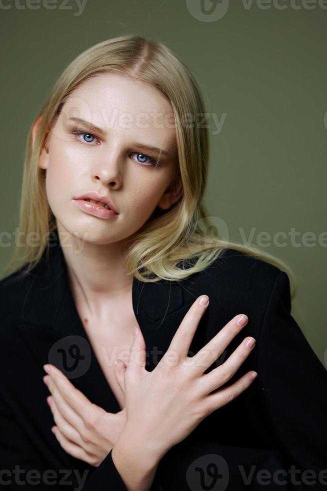 uma fechar retrato do uma Loiras cruzando dela braços em dela peito segurando uma Jaqueta de a colarinho foto