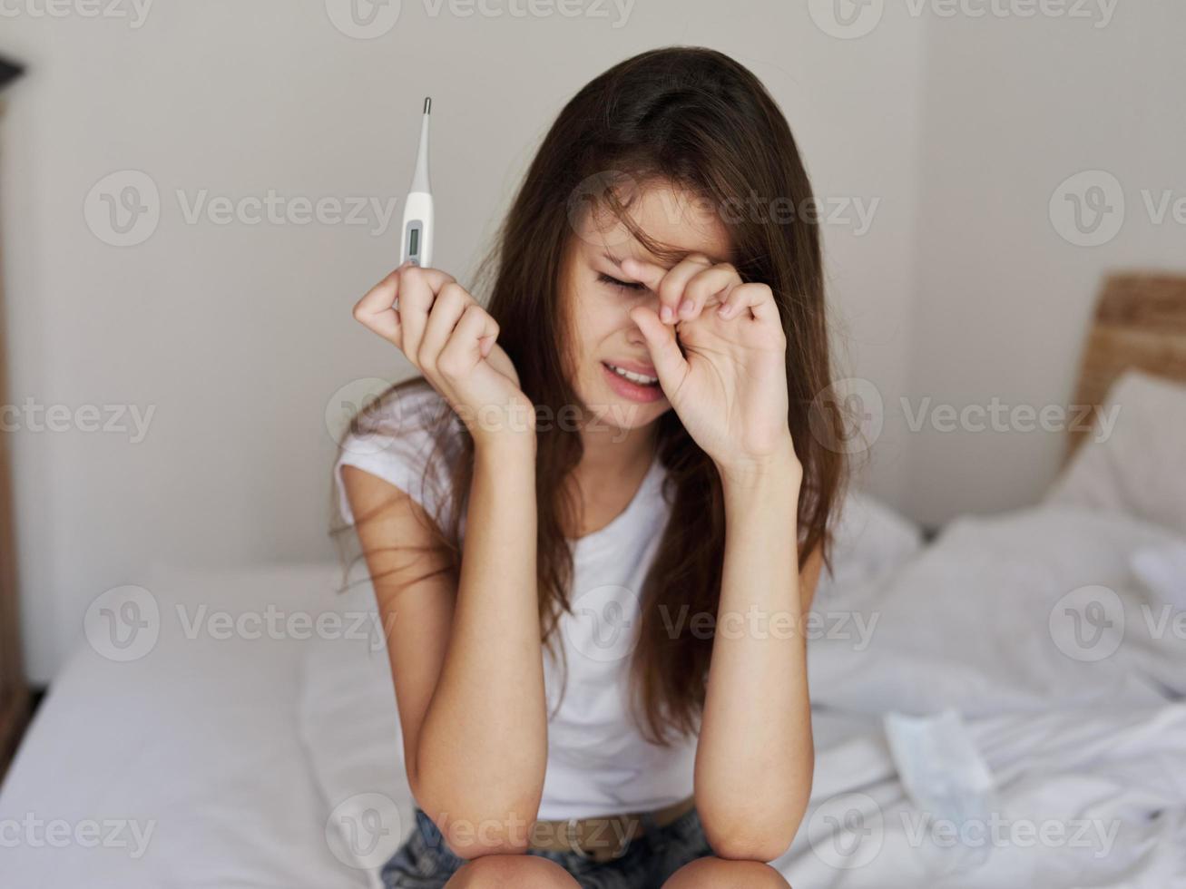 mulher com uma termômetro dentro dela mãos chateado febre foto