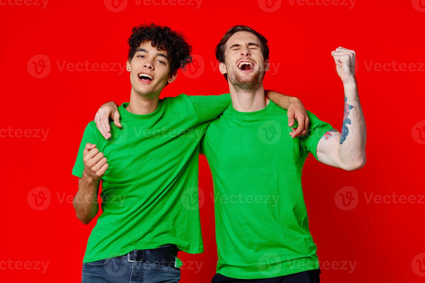 dois alegre amigos abraço verde Camisetas emoções comunicação vermelho fundo foto