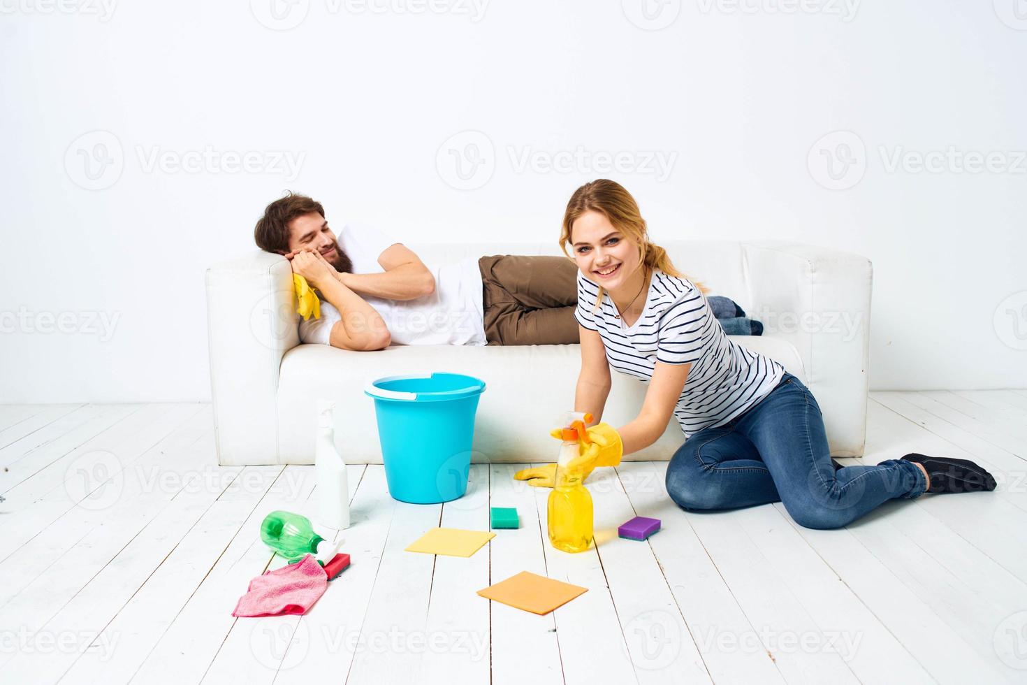 jovem casal às casa perto sofá lavando suprimentos limpeza estilo de vida foto