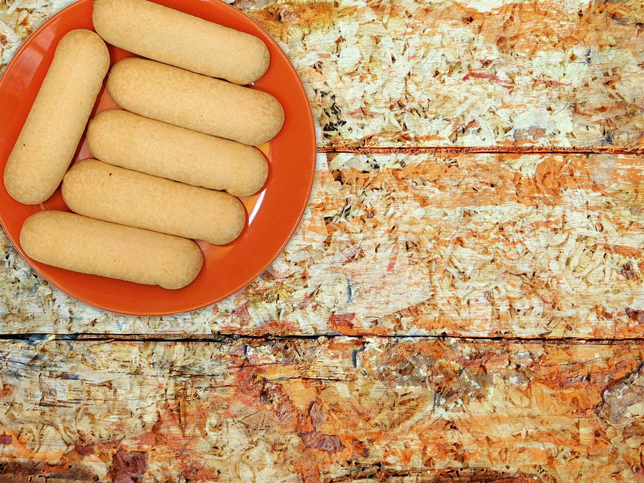 biscoitos em um prato vermelho sobre um fundo de mesa de madeira foto