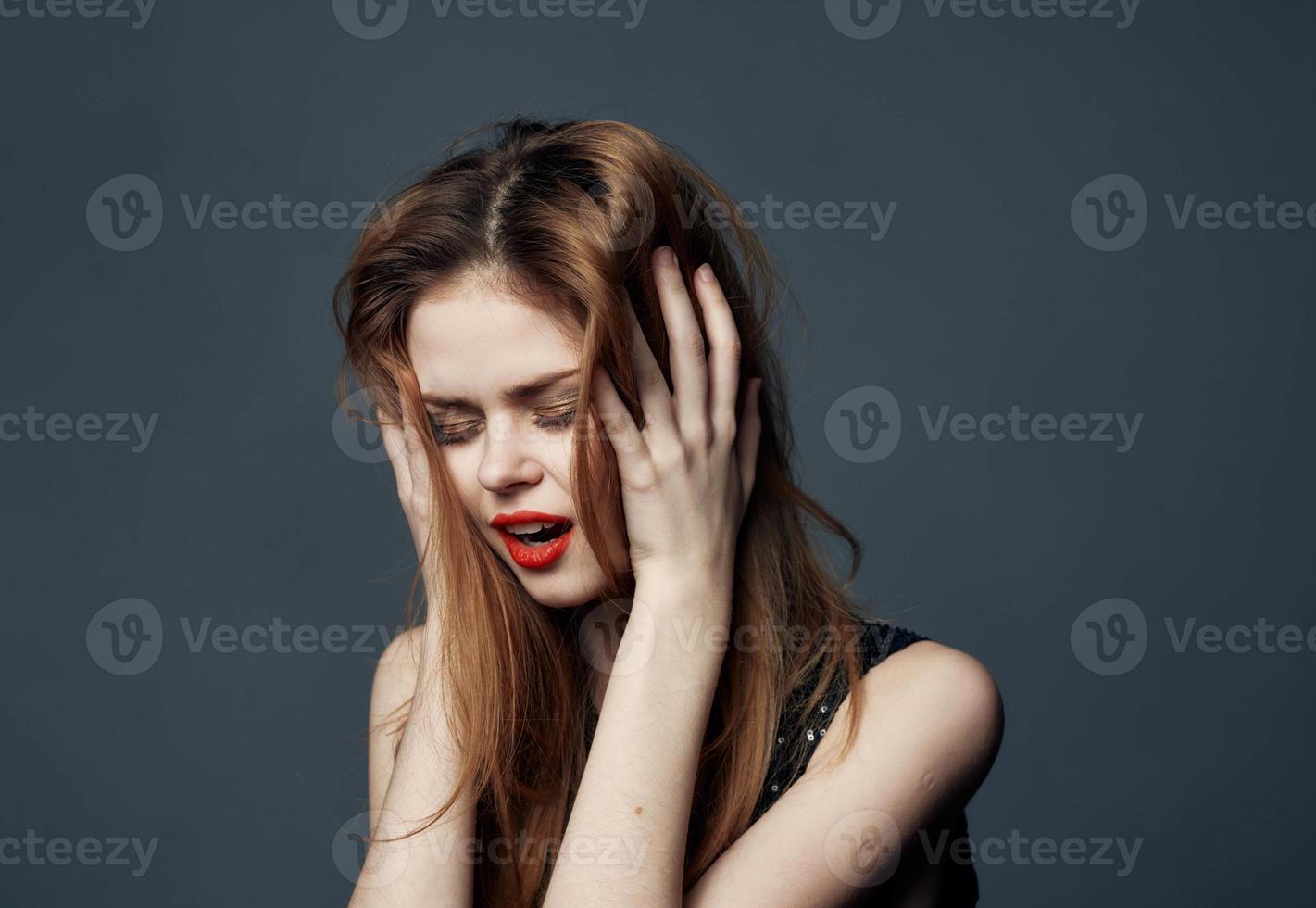 mulher com vermelho lábios chorando em cinzento fundo e mãos perto face foto