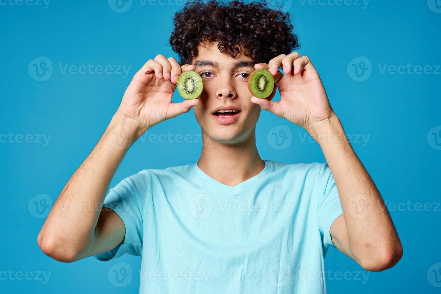 homem com kiwi encaracolado cabelo perto face azul fundo cortada Visão foto