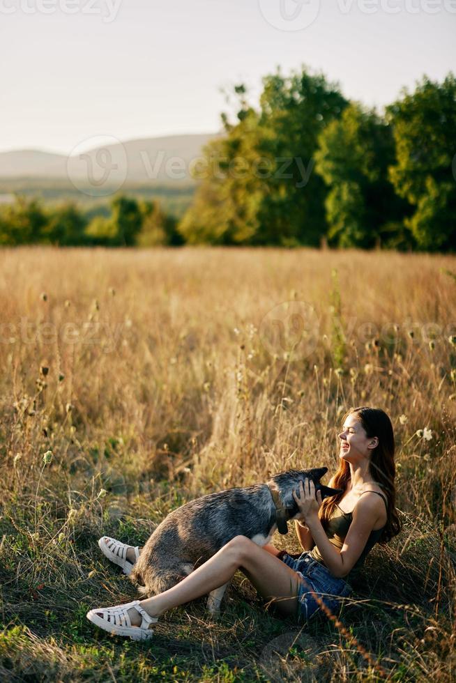 mulher sentado dentro campo com dachshund cachorro sorridente enquanto gastos Tempo dentro natureza com amigo cachorro dentro outono às pôr do sol enquanto viajando foto