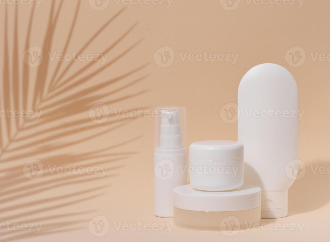 branco plástico recipiente tubo, uma jarra com uma tampa para cosméticos em uma fundo bege com uma sombra a partir de uma Palma folha. publicidade e promoção foto